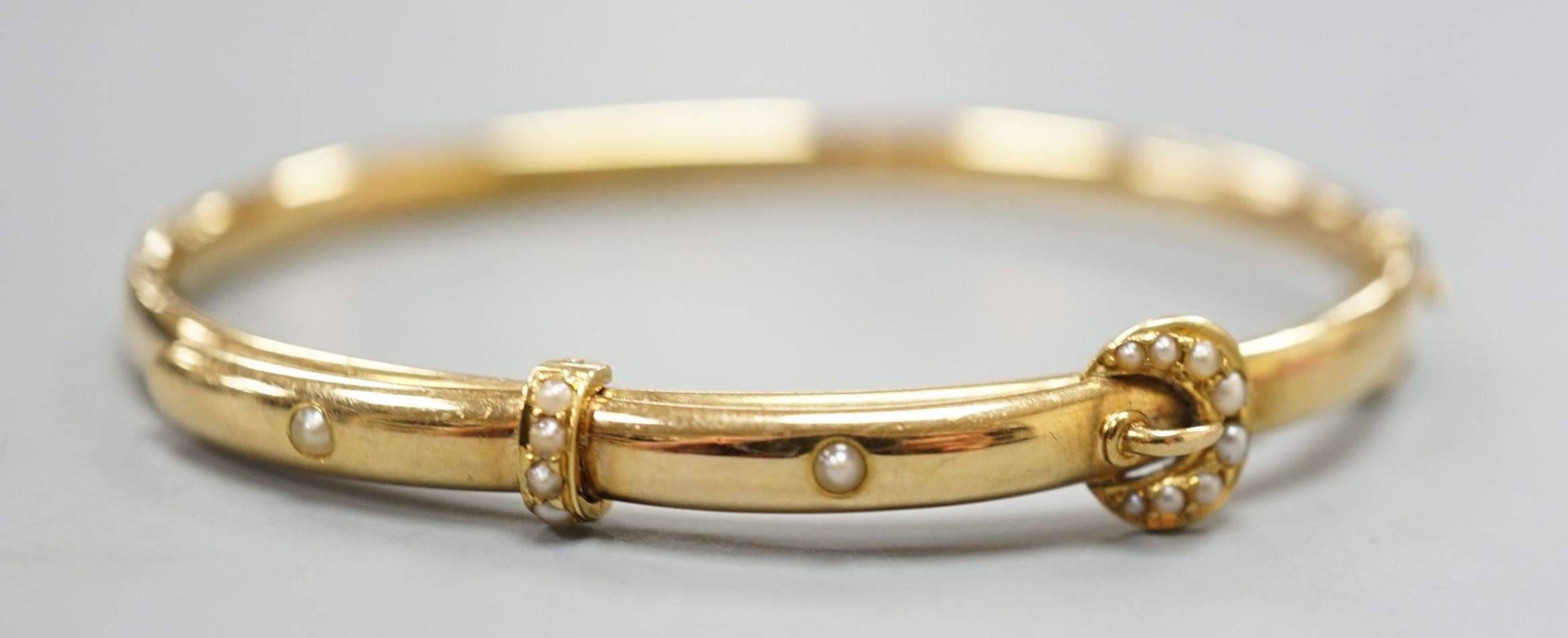 An Edwardian 15ct gold and seed pearl set hinged bracelet, interior diameter 58mm, gross weight 8.3 grams.